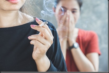 Asian woman smoking cigarette near people in family smelling pollution,passive smoking concept